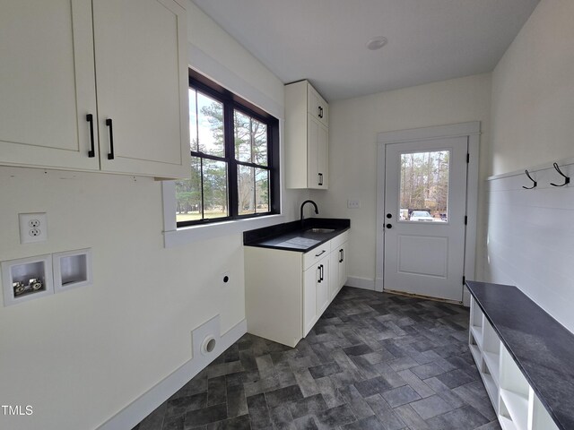 laundry room featuring electric dryer hookup, washer hookup, a sink, cabinet space, and baseboards