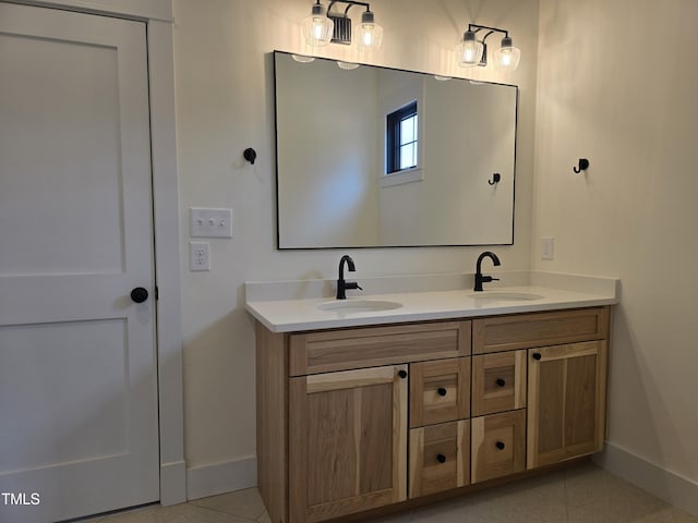 full bathroom with a sink, baseboards, double vanity, and tile patterned flooring