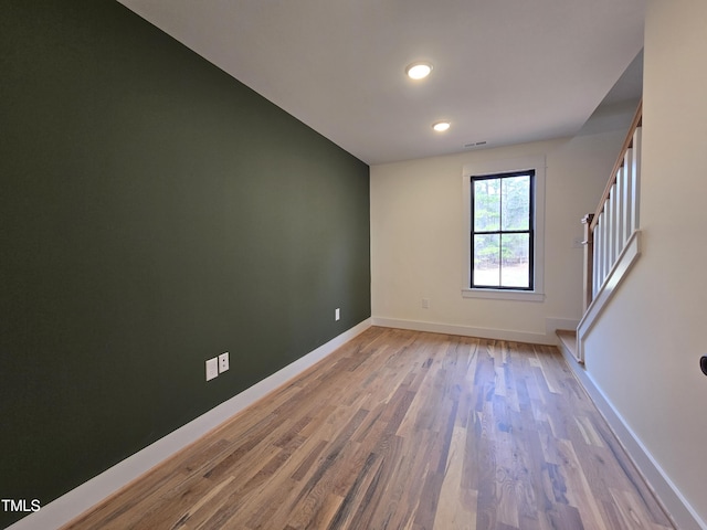 unfurnished room featuring visible vents, baseboards, stairs, and light wood finished floors