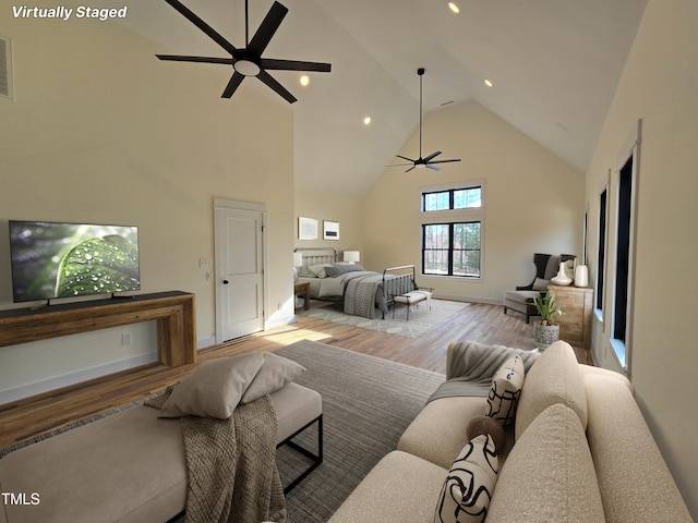 living area with visible vents, high vaulted ceiling, wood finished floors, and a ceiling fan