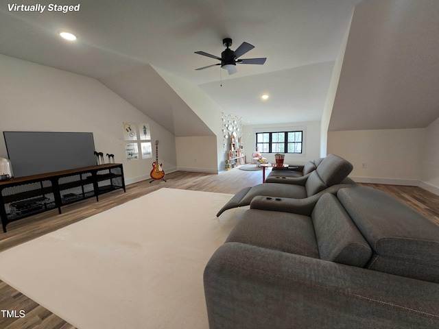 living area with baseboards, vaulted ceiling, light wood-type flooring, and a ceiling fan