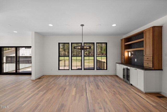 interior space featuring recessed lighting, baseboards, wine cooler, light wood-style flooring, and a notable chandelier