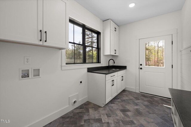 clothes washing area featuring baseboards, a sink, cabinet space, electric dryer hookup, and washer hookup