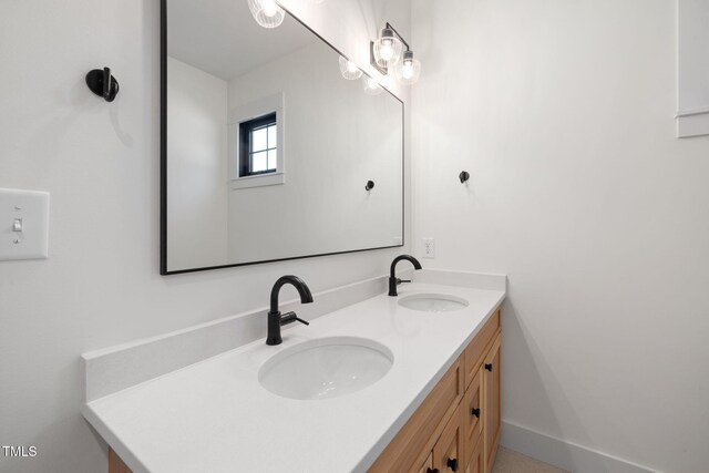 bathroom with baseboards, double vanity, and a sink