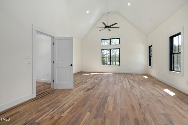 empty room with baseboards, high vaulted ceiling, wood finished floors, and ceiling fan