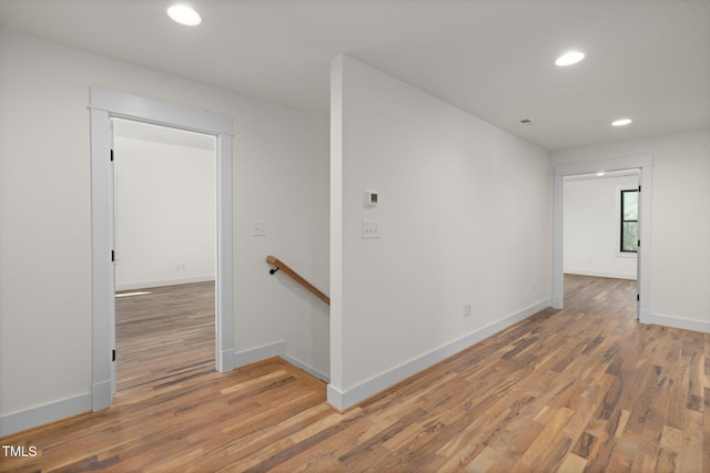 interior space with baseboards, an upstairs landing, wood finished floors, and recessed lighting