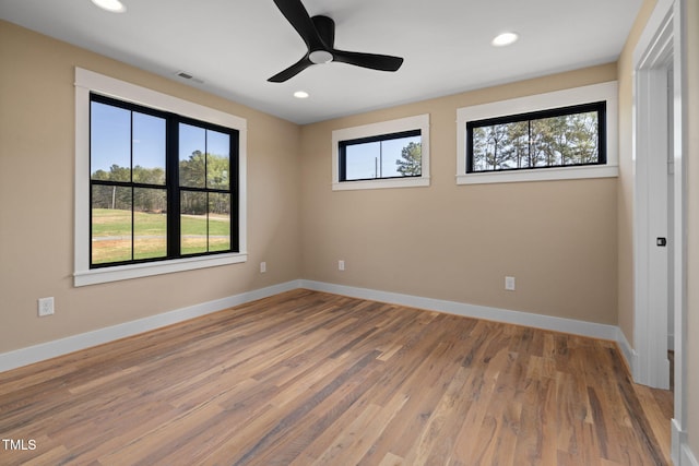 unfurnished bedroom featuring multiple windows, visible vents, wood finished floors, and baseboards