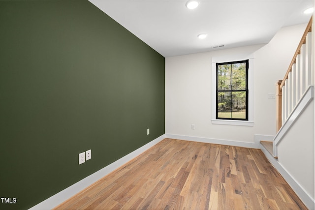 spare room with visible vents, baseboards, stairs, wood finished floors, and recessed lighting
