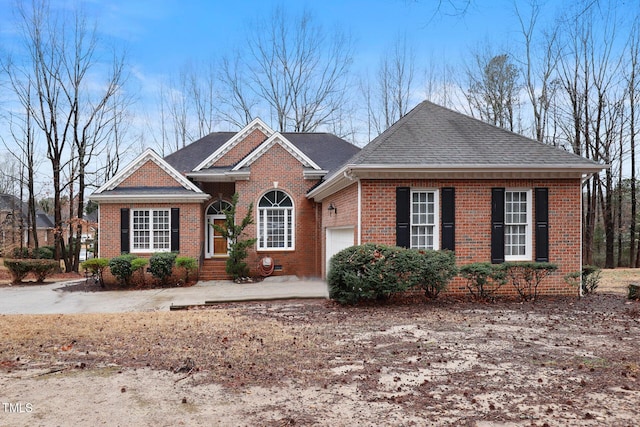 single story home featuring a garage, brick siding, and a shingled roof