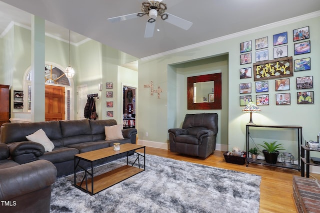 living area with baseboards, crown molding, a ceiling fan, and wood finished floors