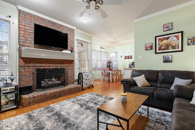 living area with a fireplace, wood finished floors, a ceiling fan, and ornamental molding