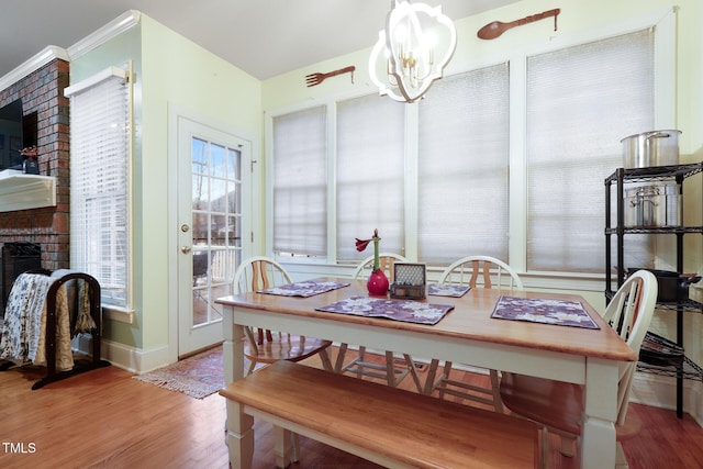 dining room with baseboards, an inviting chandelier, wood finished floors, and a fireplace