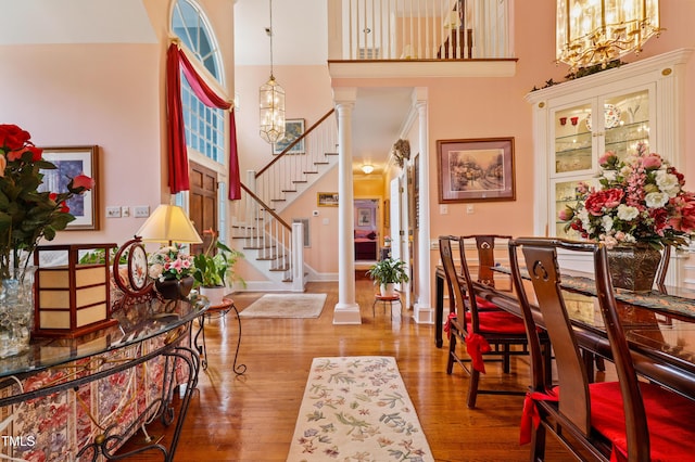 dining area featuring a notable chandelier, stairway, a towering ceiling, and wood finished floors