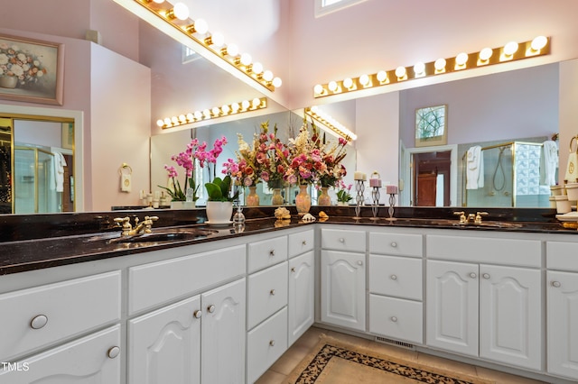 bathroom featuring double vanity, a stall shower, and a sink