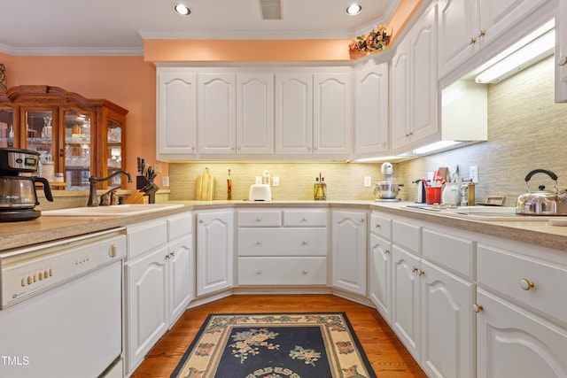 kitchen with light wood-type flooring, ornamental molding, a sink, white dishwasher, and light countertops