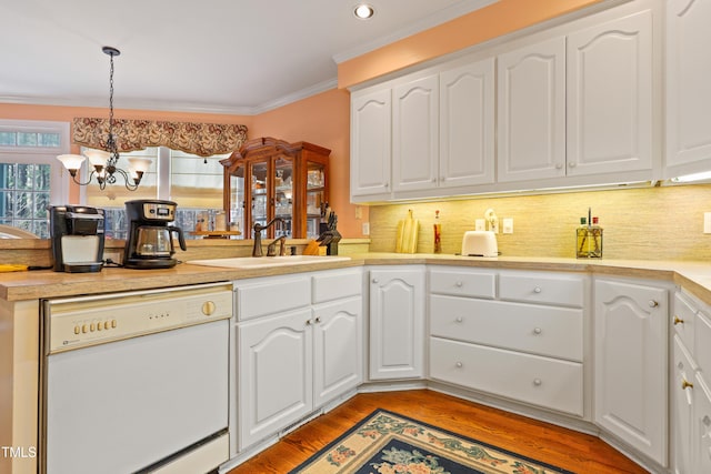 kitchen with ornamental molding, a sink, light wood finished floors, dishwasher, and a chandelier