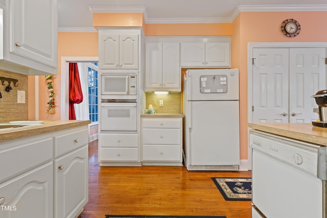 kitchen with white appliances, light wood-style floors, white cabinets, crown molding, and decorative backsplash