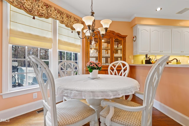 dining area featuring visible vents, crown molding, baseboards, an inviting chandelier, and wood finished floors