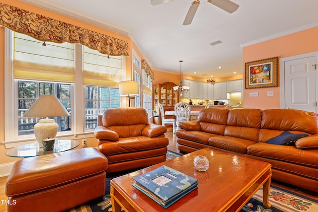 living room featuring visible vents, baseboards, ceiling fan, ornamental molding, and wood finished floors