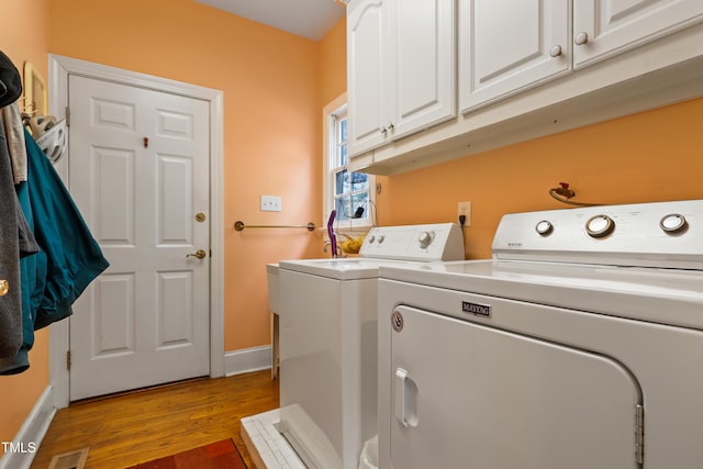 laundry room with visible vents, baseboards, wood finished floors, cabinet space, and separate washer and dryer