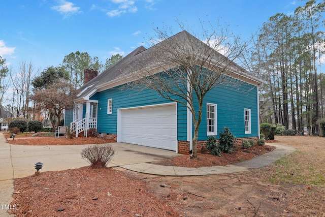 view of side of property with a chimney, an attached garage, and concrete driveway