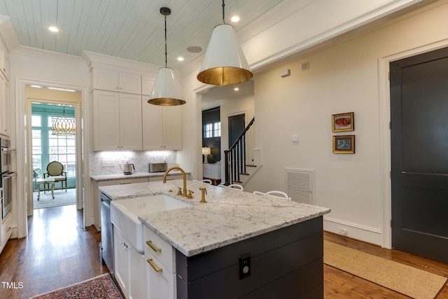 kitchen with dark wood finished floors, tasteful backsplash, visible vents, ornamental molding, and white cabinets