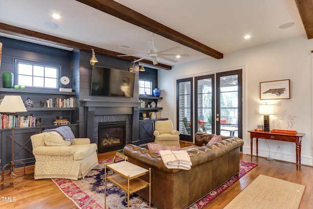 living room with recessed lighting, a fireplace, beamed ceiling, and wood finished floors