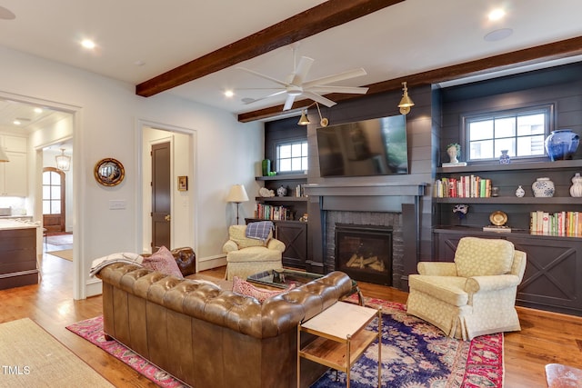 living area with recessed lighting, a fireplace, beamed ceiling, and wood finished floors