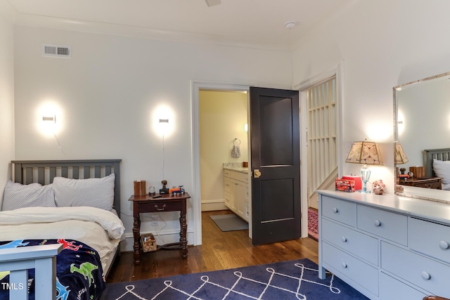 bedroom featuring visible vents, crown molding, ensuite bathroom, and wood finished floors