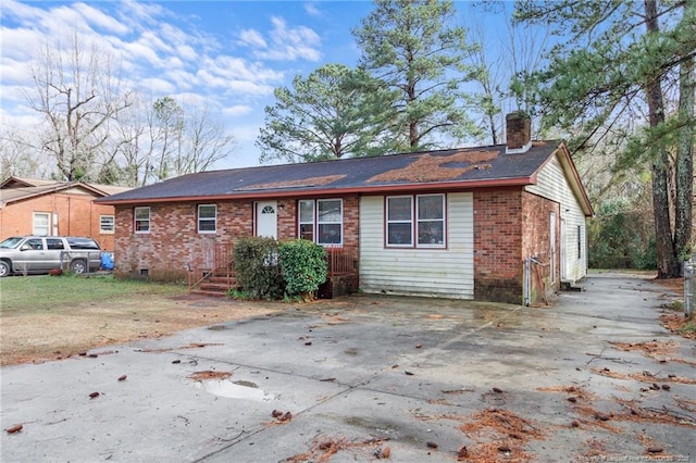 view of front facade with crawl space, brick siding, and a chimney