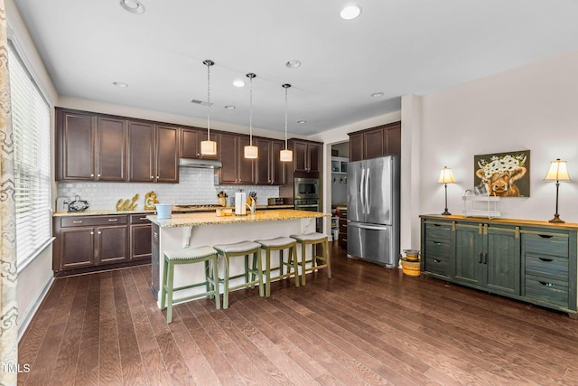 kitchen featuring under cabinet range hood, appliances with stainless steel finishes, dark wood-type flooring, and dark brown cabinets