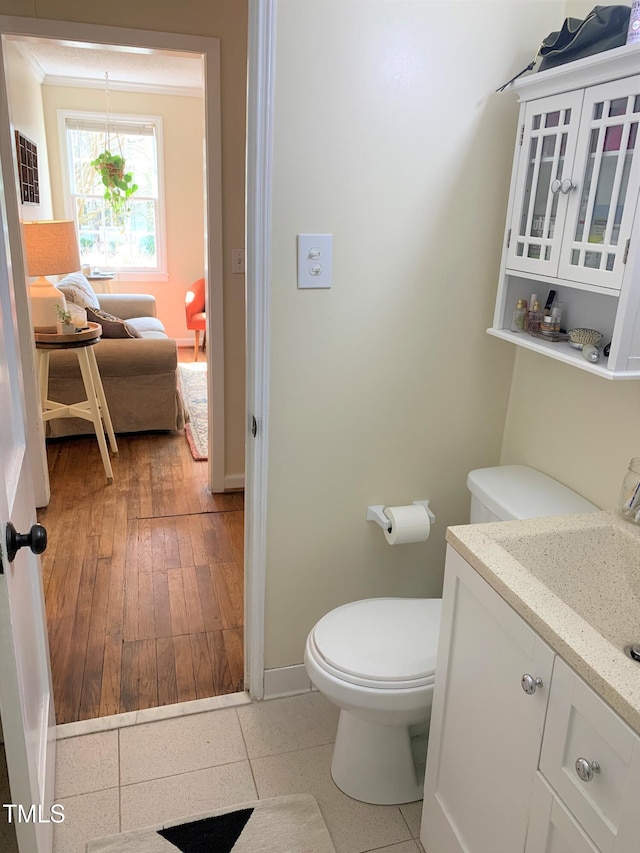 half bath featuring tile patterned floors, vanity, toilet, and baseboards