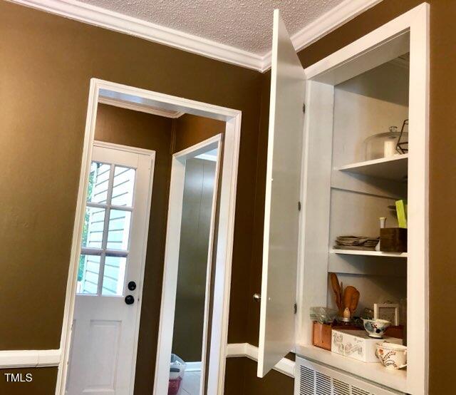 doorway featuring ornamental molding and a textured ceiling