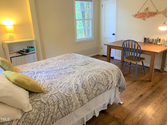 bedroom with radiator heating unit, baseboards, and wood finished floors