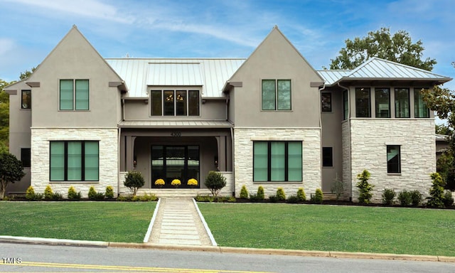 view of front of property featuring a standing seam roof, a front yard, stone siding, and metal roof