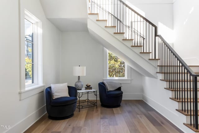 living area featuring baseboards, wood finished floors, and stairs