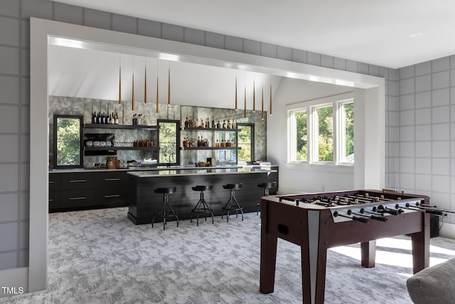 recreation room featuring a dry bar and tile walls