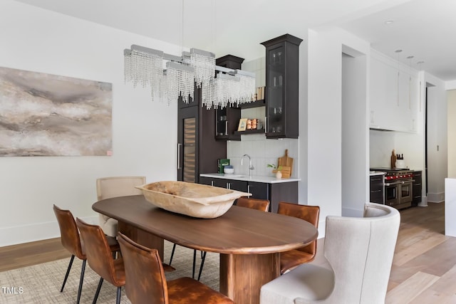 dining room featuring indoor wet bar, baseboards, and light wood-style flooring