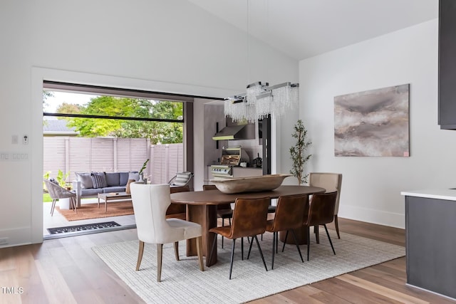 dining area with wood finished floors, baseboards, and high vaulted ceiling