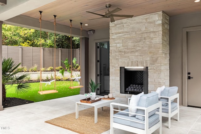 view of patio with a ceiling fan, fence, and an outdoor stone fireplace