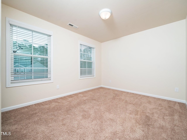 carpeted empty room with visible vents and baseboards