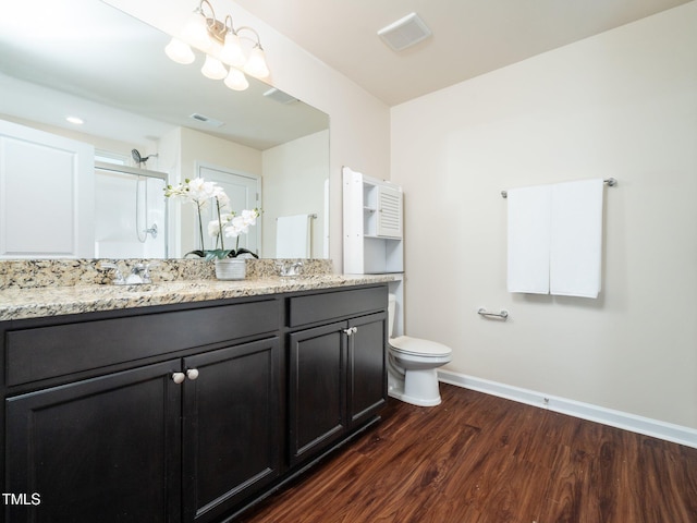 full bathroom featuring a stall shower, baseboards, visible vents, wood finished floors, and a sink