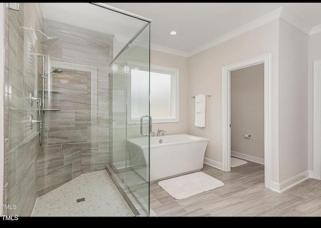 bathroom with a freestanding bath, a stall shower, baseboards, and crown molding