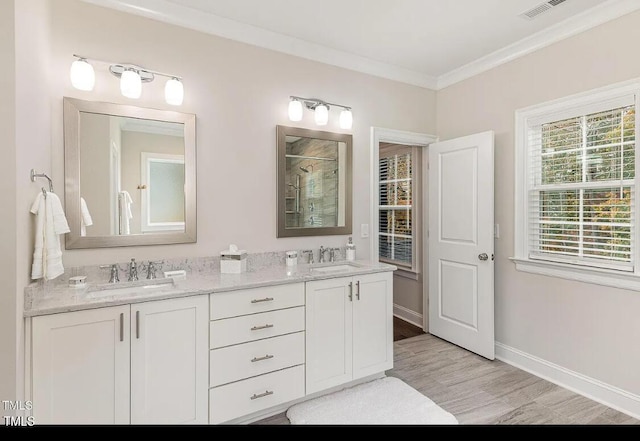 bathroom featuring crown molding, visible vents, a tile shower, a sink, and baseboards