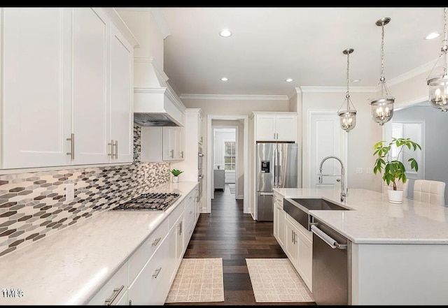 kitchen with stainless steel appliances, a sink, white cabinetry, decorative backsplash, and a center island with sink