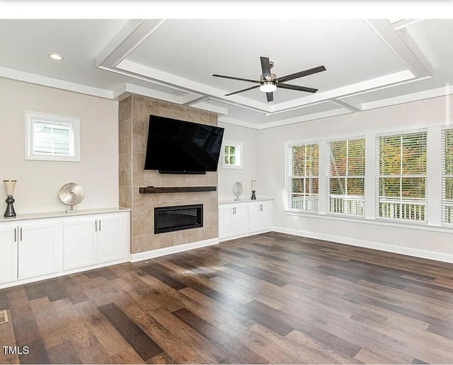 unfurnished living room with dark wood-style floors, a raised ceiling, a fireplace, and ceiling fan