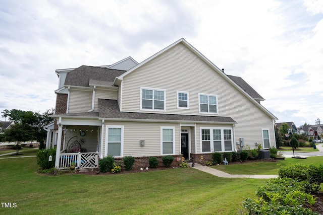 view of front of property with brick siding, roof with shingles, and a front yard