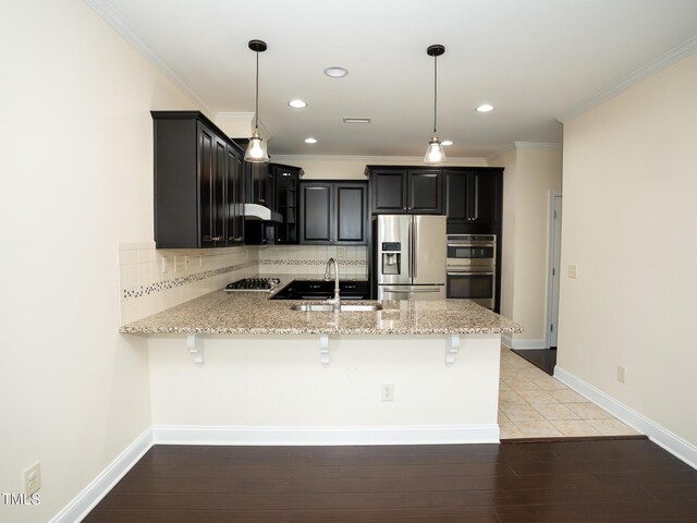 4137 Strendal Dr, Cary, NC 27519 - kitchen featuring backsplash, appliances with stainless steel finishes, a sink, a peninsula, and dark cabinetry