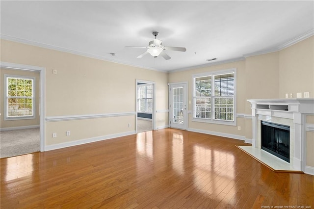 unfurnished living room featuring visible vents, ceiling fan, ornamental molding, wood finished floors, and a fireplace