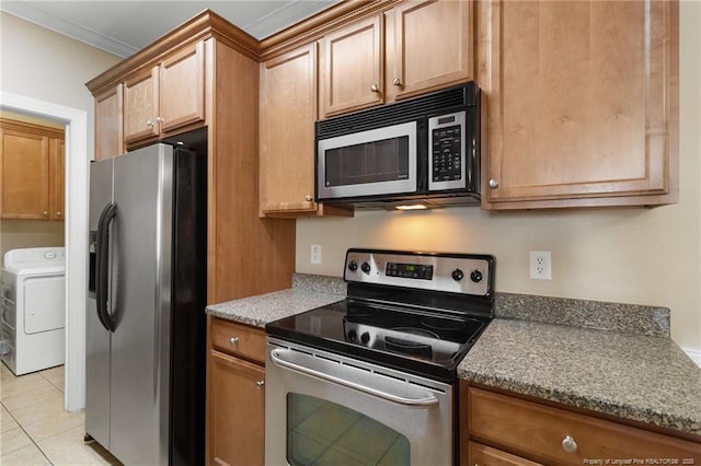 kitchen featuring stainless steel appliances, washer / dryer, crown molding, and light tile patterned floors